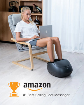 A woman sitting in a modern chair uses a laptop on her lap while resting her feet in a Renpho EU Shiatsu Foot Massager Premium. The setting suggests a comfortable, stylish home environment.