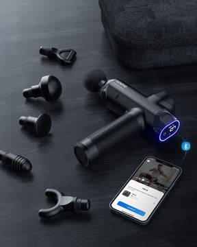 A RENPHO Power Massage Gun with various attachments is displayed on a dark textured surface. Nearby, an open carrying case, a smartphone showing a wellness app, and a pair of earbuds add to the high-tech aesthetic.