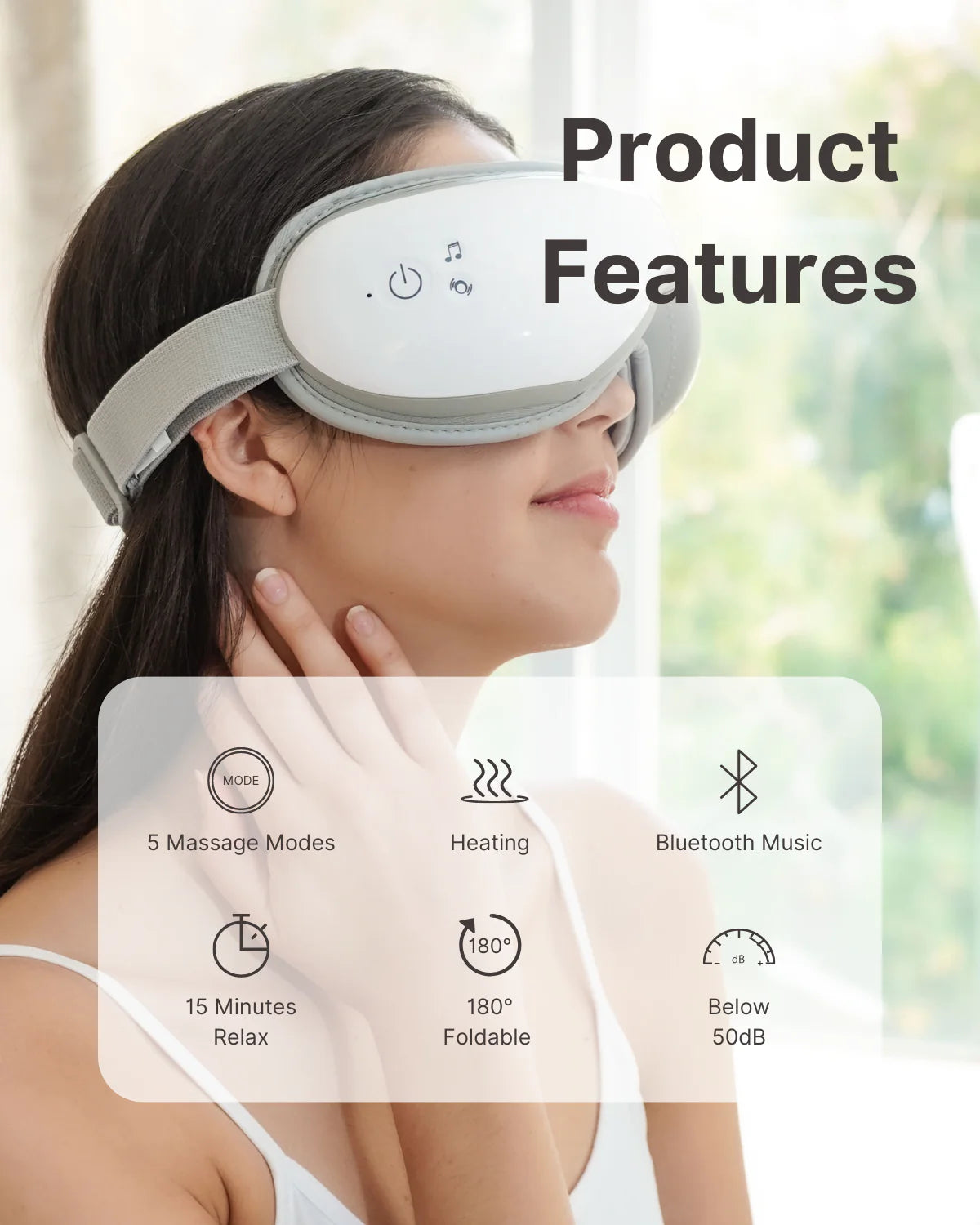 A woman wearing a white Renpho EU Eyeris 1 Eye Massager with massage and heating functions advertised by accompanying icons detailing features like Bluetooth music, 180-degree heat, and quiet operation. She smiles slightly, experiencing the mask indoors.