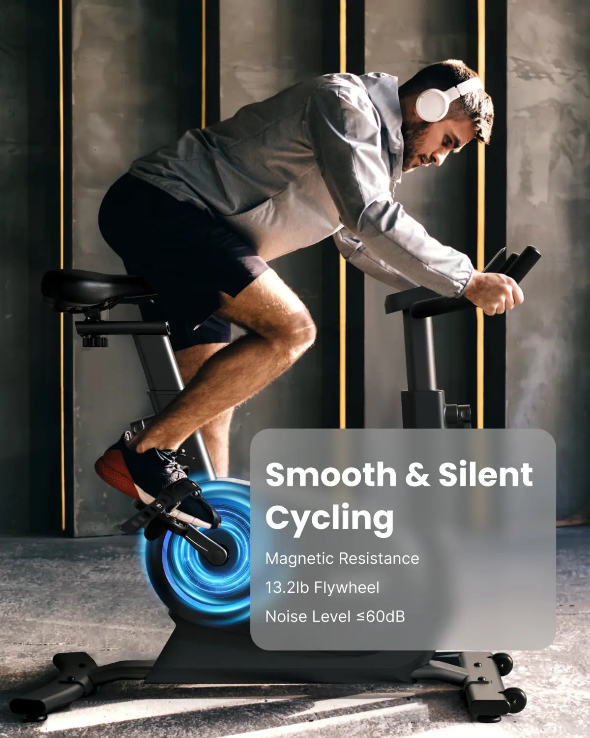 A man wearing a gray hoodie and black shorts rides a Renpho EU AI Smart Bike S indoors. He has white headphones on and is focused on cycling. The AI Smart Bike S features a blue flywheel, offering an immersive fitness experience. Text overlay reads "Smooth & Silent Cycling", "Magnetic Resistance 13.2lb Flywheel", and "Noise Level ≤60dB".