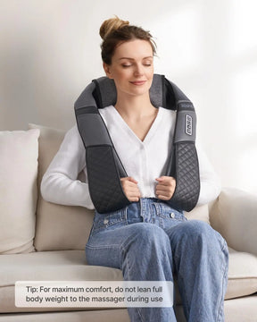 A woman sits on a white couch with her eyes closed, appearing relaxed. She wears a white sweater, blue jeans, and uses a Renpho EU U-Neck 2 Neck & Shoulders Massager with built-in heating. Her hair is tied up. A tip on the image advises not to lean full body weight on the massager for maximum comfort.